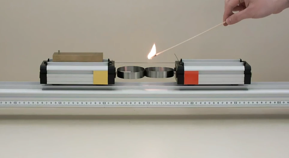 Two cars of different mass being pushed apart by a spring